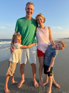 Happy family standing barefoot on a sunny beach together, smiling and hugging.